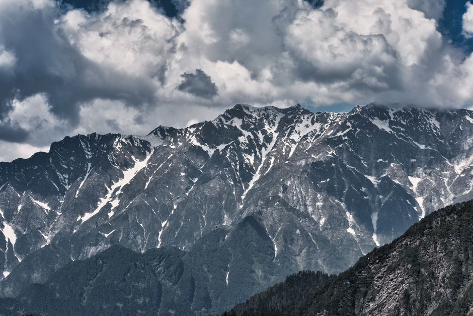Rugged snow-streaked Himalayan mountain range under a dramatic cloudy sky